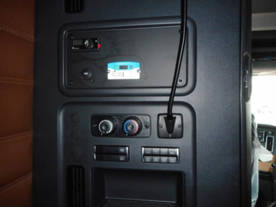 Conventional sleeper truck cab interior panel showing controls and a blue placard with VIN plate.