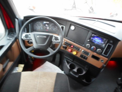 Freightliner Cascadia 126 cab interior showing steering wheel, dashboard with gauges, infotainment screen, and control panel.