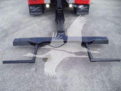 Tow hitch assembly with wheel-lift arms and rear of a Ford F-450 truck visible in background.