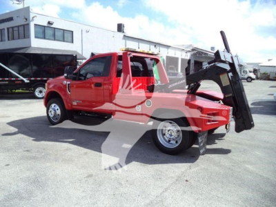 Ford F-450 XLT tow truck with a raised bed and hydraulic lift in a dealership lot.