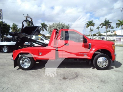 Ford F-450 with front winch, red cab and flatbed, side view showing winch mechanism and label stickers.