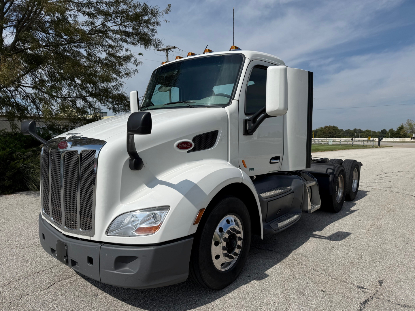 Peterbilt 579 daycab tractor in white, front three-quarter view showing grille, headlights, and side mirrors.