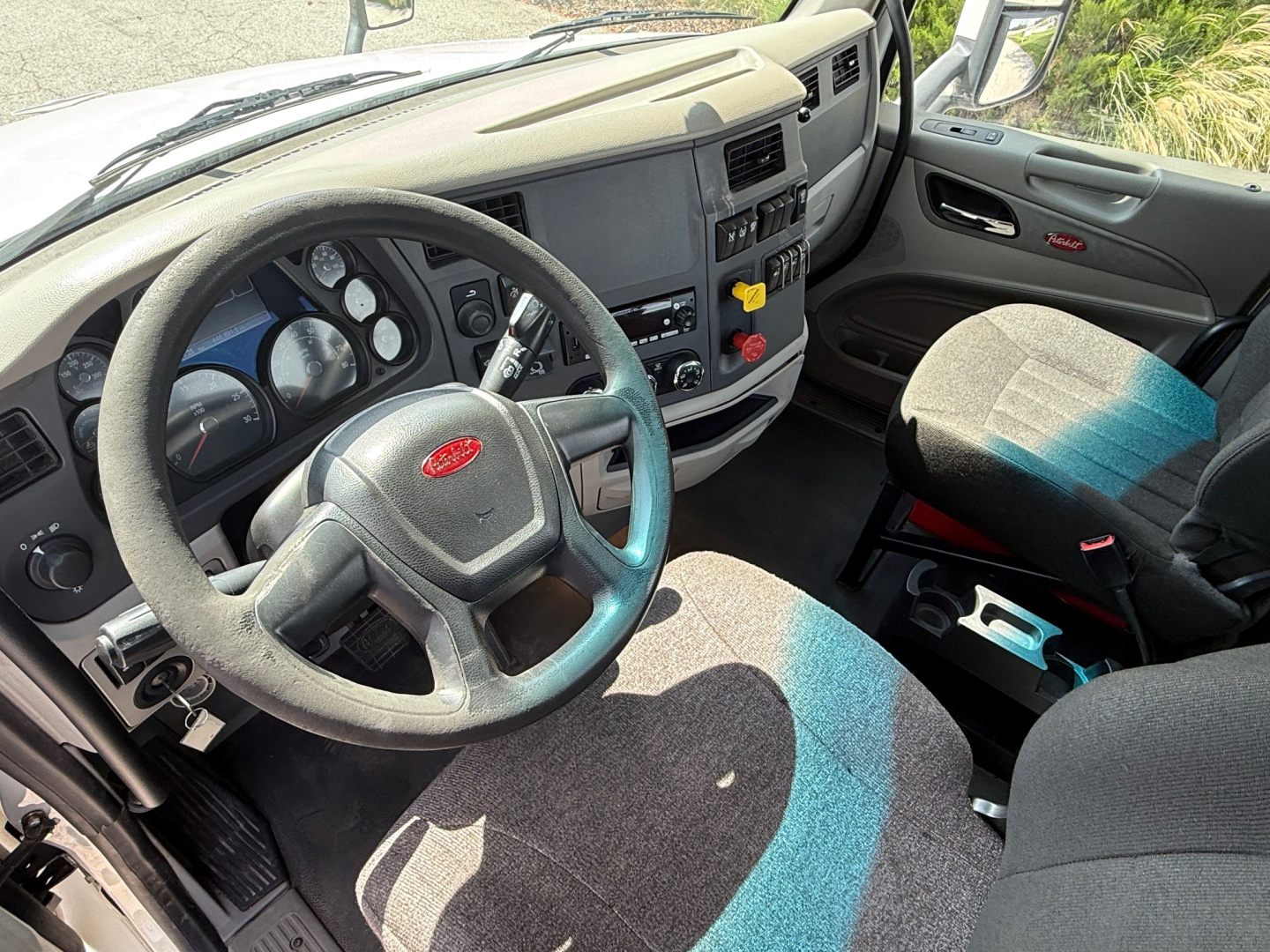 Peterbilt 579 truck interior showing steering wheel with Peterbilt emblem, dashboard gauges, driver seat, and center console.