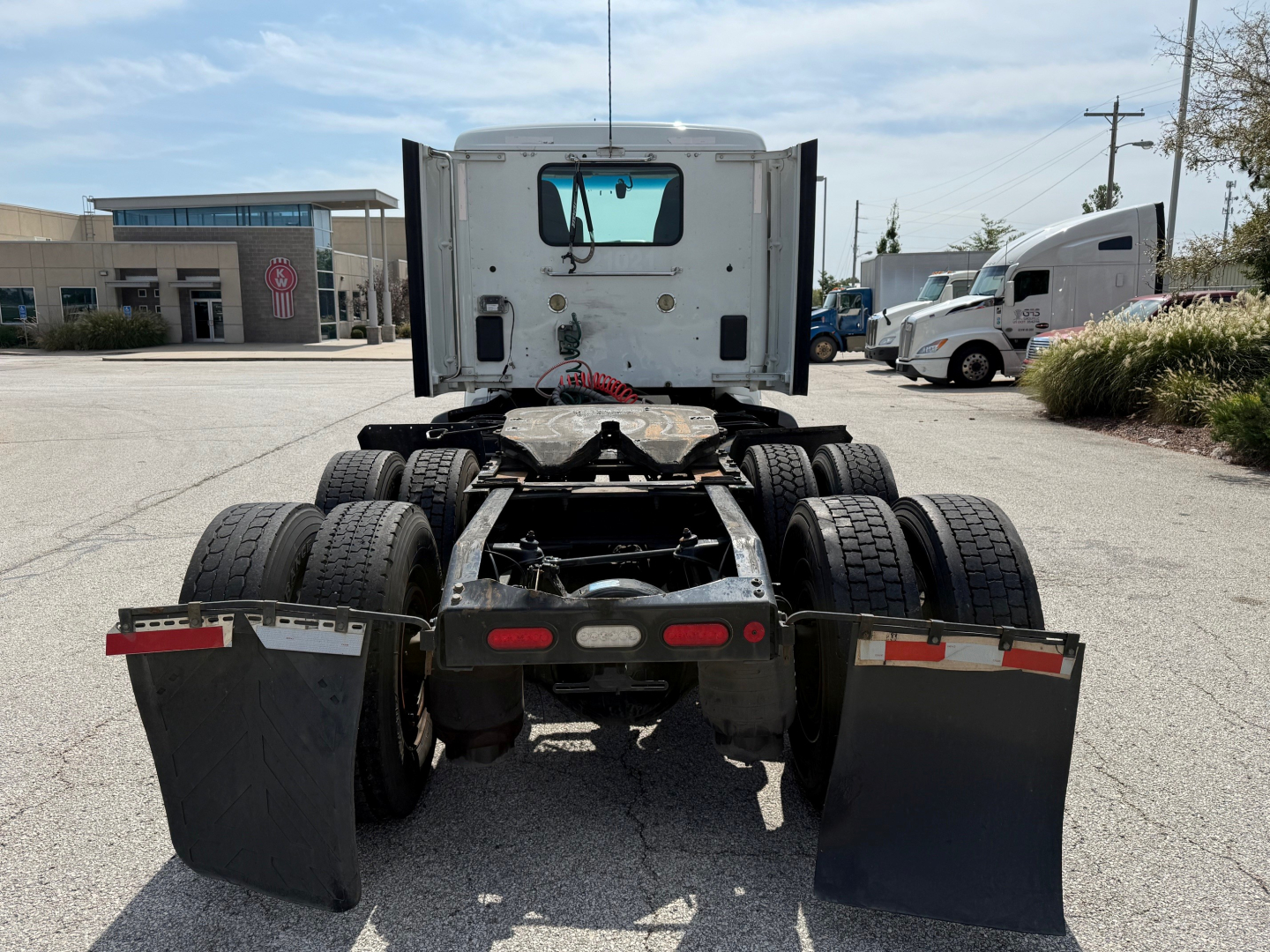 Peterbilt 579 tractor rear view showing fifth wheel hitch, dual rear axles, and mud flaps in a truck lot.