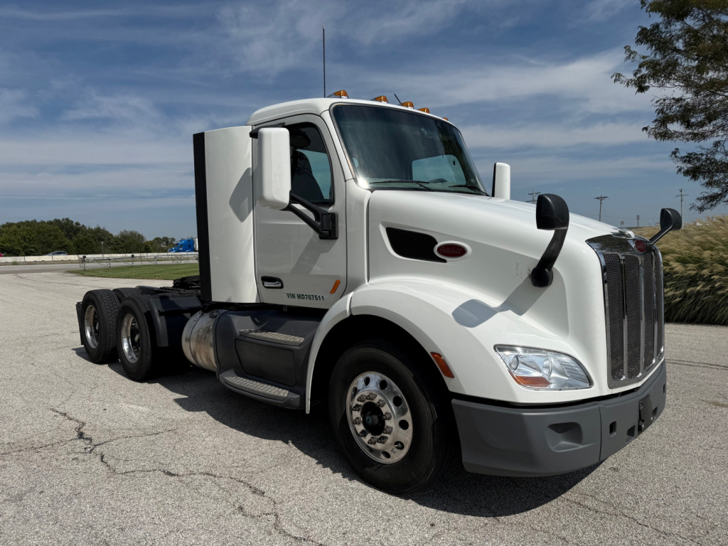 Peterbilt 579 truck cab side view with white paint, tandem rear axles, black trim, and a large grille.