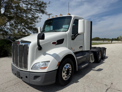 Peterbilt 579 daycab tractor in white, front three-quarter view showing grille, headlights, and side mirrors.
