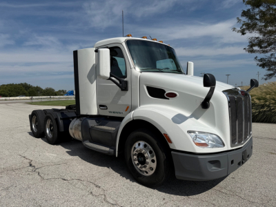 Peterbilt 579 truck cab side view with white paint, tandem rear axles, black trim, and a large grille.