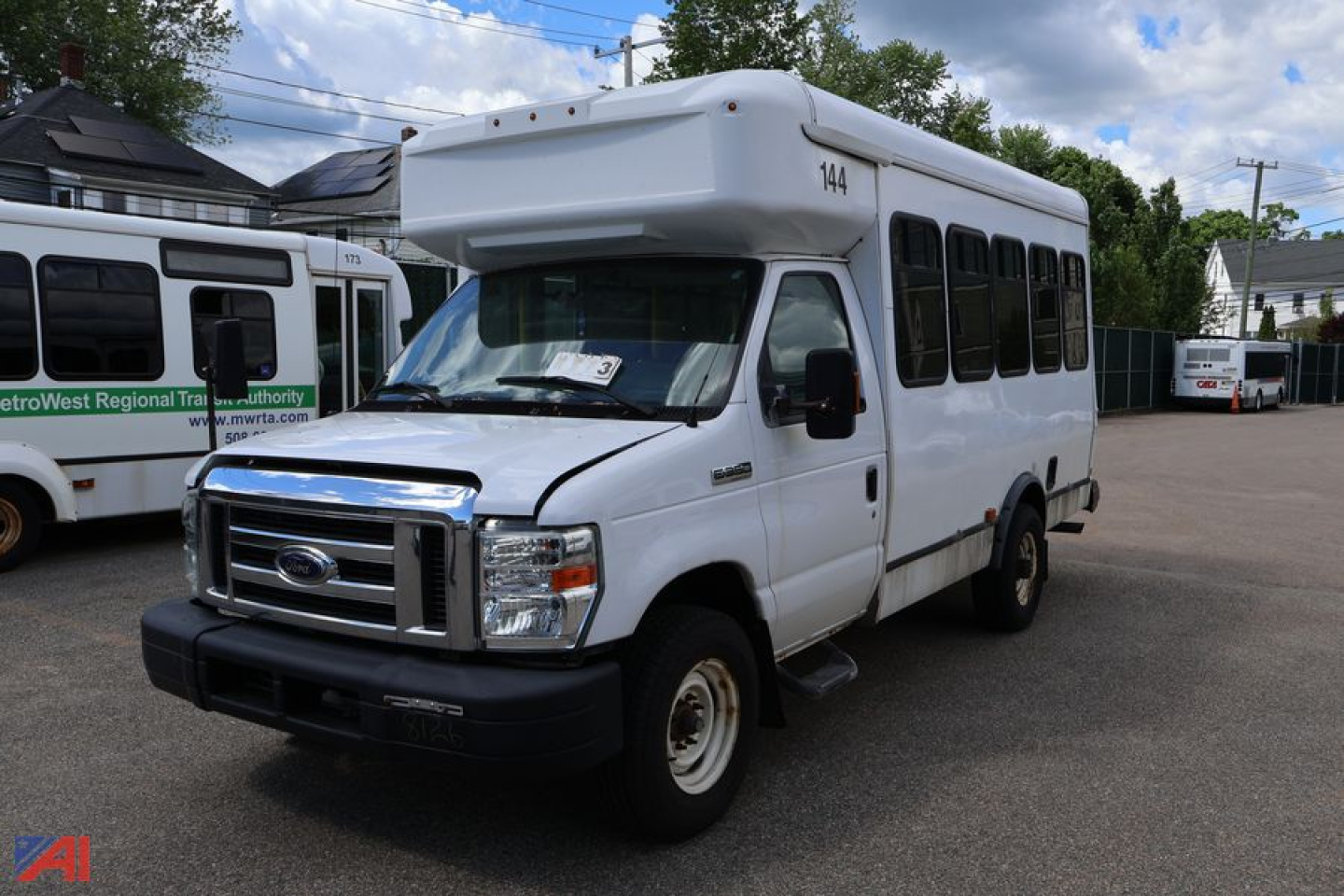 Ford E350 shuttle bus in white, front-side view showing roof wheelchair lift housing and passenger windows.