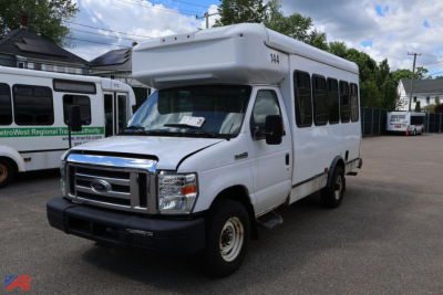 Ford E350 shuttle bus in white, front-side view showing roof wheelchair lift housing and passenger windows.