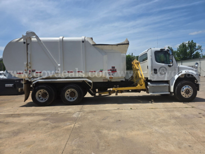 Freightliner M2 garbage truck side view showing rear compactor body and cab with yellow step platform.