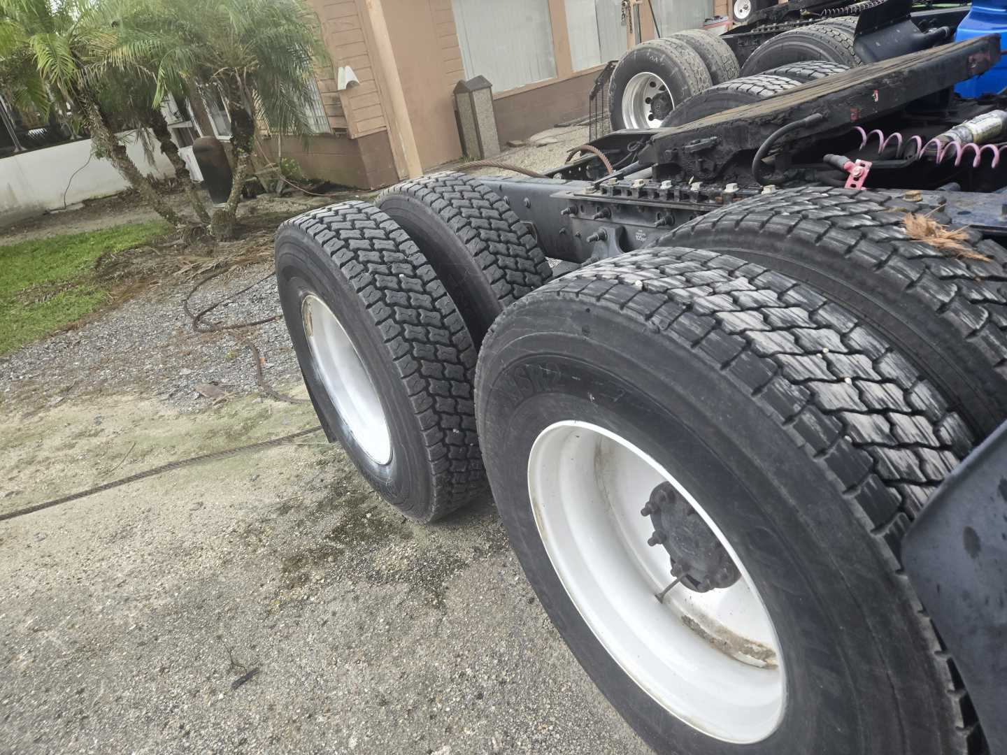 Truck chassis showing dual rear axles with white rims and heavy duty tires; no cab in frame, Cummins engine bay not visible.