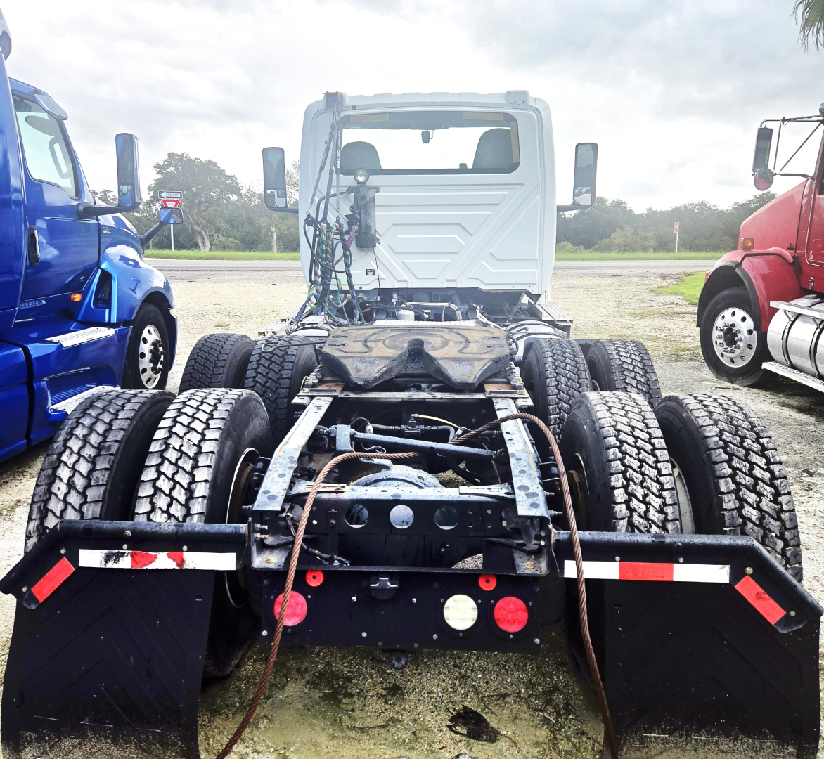 Truck chassis rear view showing dual rear axles, fifth-wheel area, and dual mud flaps.