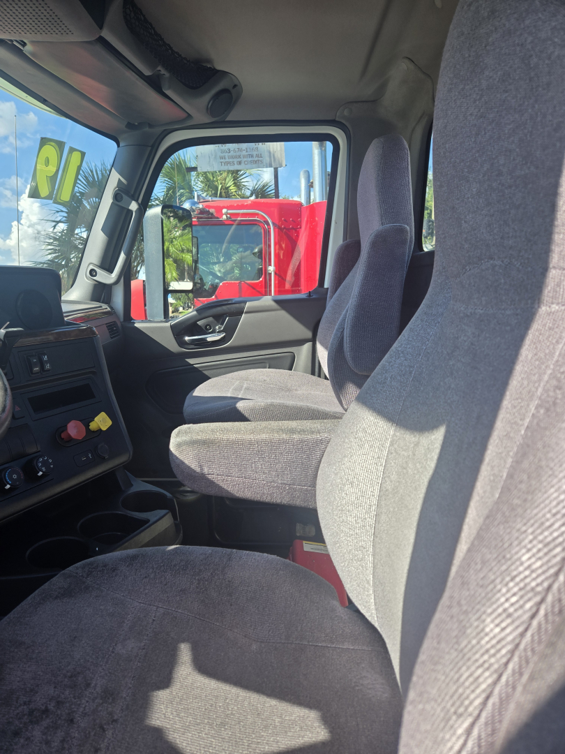Interior driver's seat and dashboard of a 2019 International LT625 daycab showing steering wheel, center console, and fabric seats.