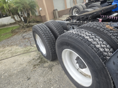 Truck chassis showing dual rear axles with white rims and heavy duty tires; no cab in frame, Cummins engine bay not visible.