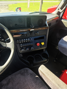 Cab interior of 2019 International LT625 DAYCAB showing dashboard with steering wheel, switches, cup holders, and seating.