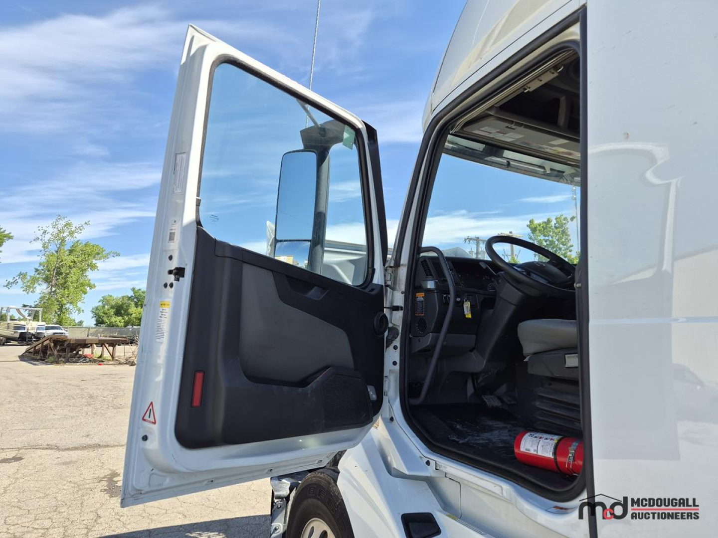Cab opening door of a Volvo VNL760 Day Cab showing interior steering wheel and open door with dash and seat.