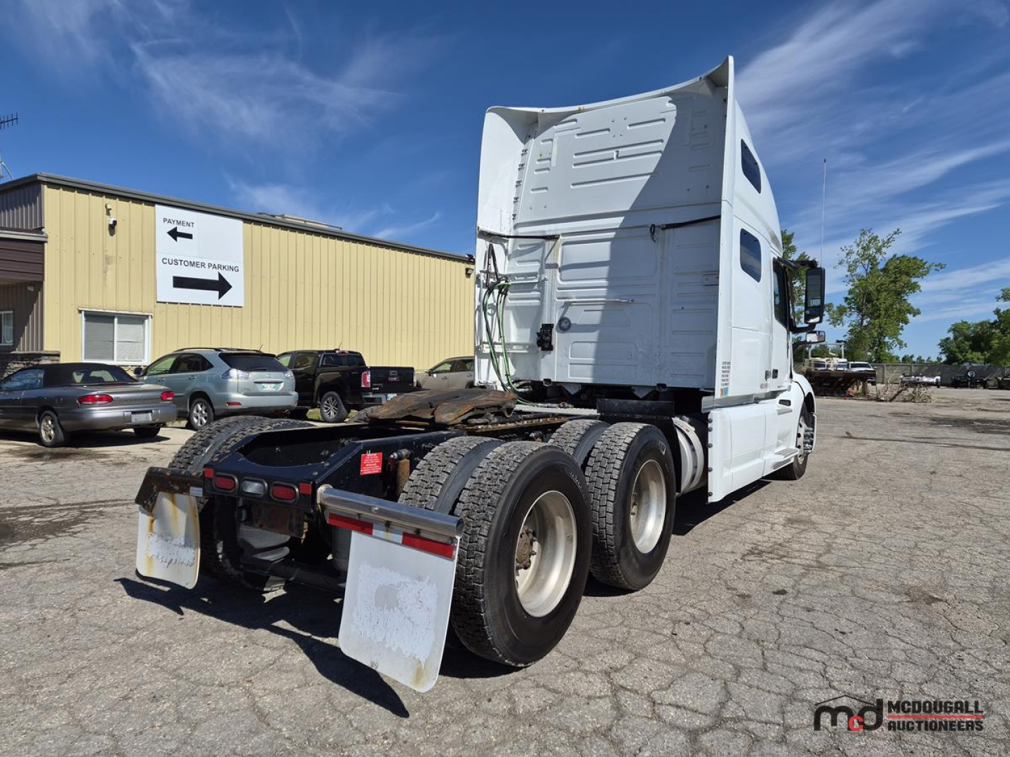 2022 Volvo VNL760 day cab tractor rear view showing triple rear axles, fifth wheel, and mud flaps. Visible text on side shows Volvo branding and model features; license-like plate area present.