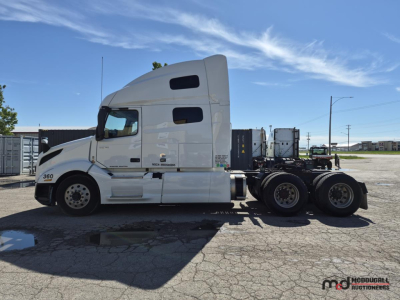 Side view of a white Volvo VNL760 day cab truck tractor showing sleeper cab and rear triple axle, with no visible text readable on side windows or panels.