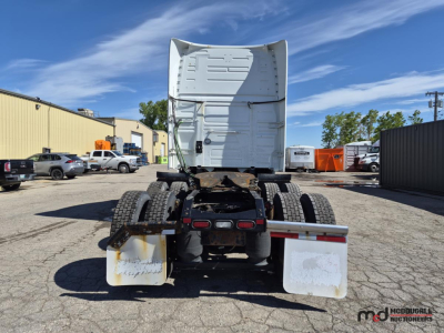 Truck rear view showing chassis and dual rear axles with mud flaps and white sleeper cab behind. Visible tail lights and rear bumper assembly.