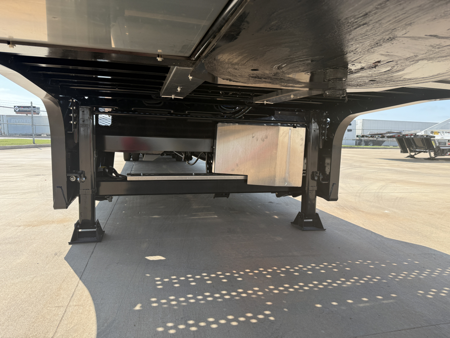 Low-angle underside view of a Landoll 455B-53 trailer showing support legs and frame undercarriage.