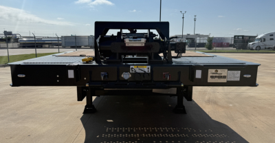 Landoll 455B-53 lowboy trailer rear view showing 55 ton traveling axle and hookup components with badge labels and safety decals.