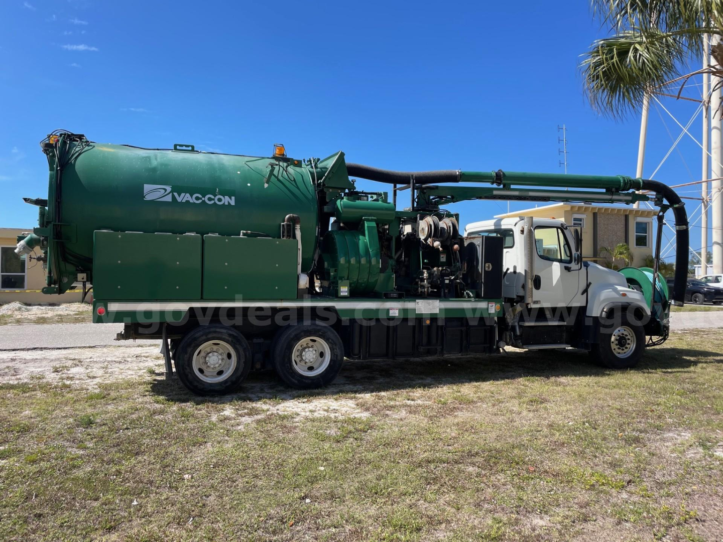 Freightliner 114SD vacuum truck with large green vacuum tank and hoses, side view showing Vac-Con branding.