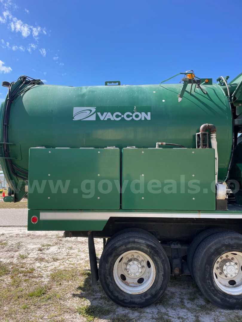 Vac-con vacuum truck tank side showing VAC-CON logo and two large access panels with wheels visible at bottom.