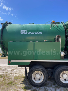 Vac-con vacuum truck tank side showing VAC-CON logo and two large access panels with wheels visible at bottom.