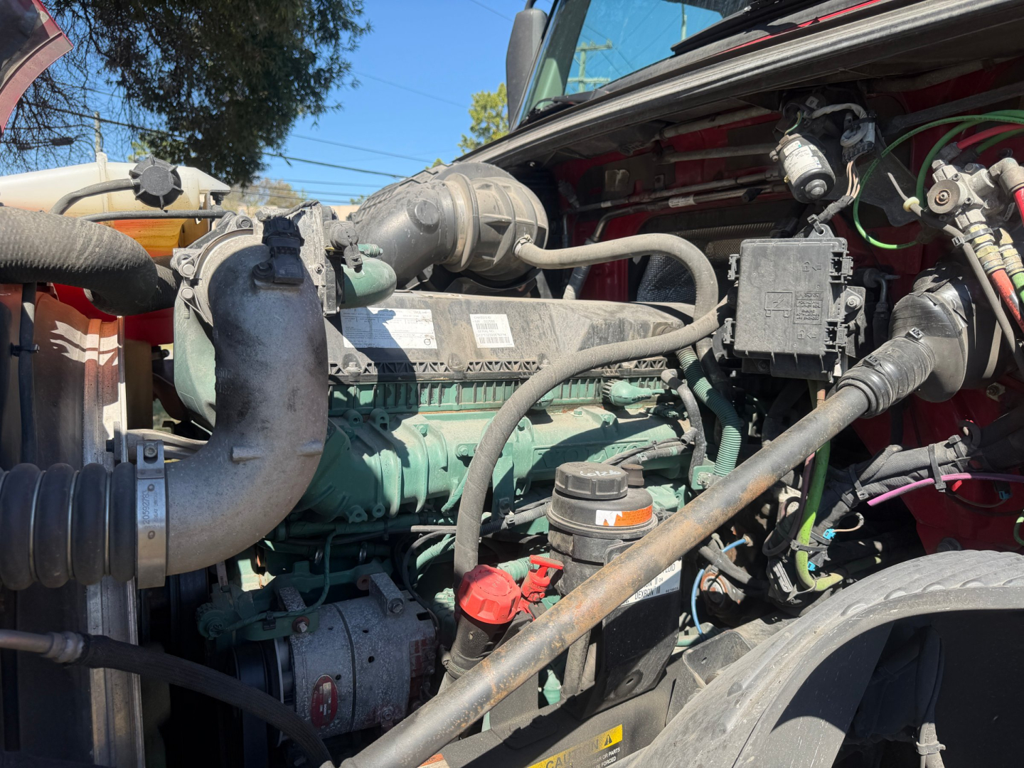 Volvo VNL64T760 engine bay showing diesel engine with green components, hoses, and wiring harnesses