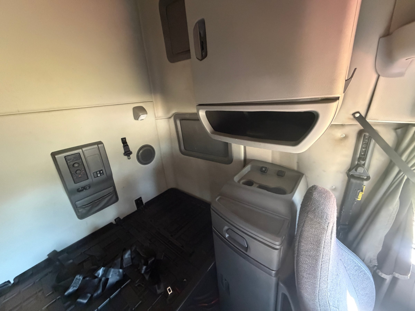 Volvo VNL64T760 sleeper cab interior showing dash area, overhead storage, and driver's seat with window controls visible.