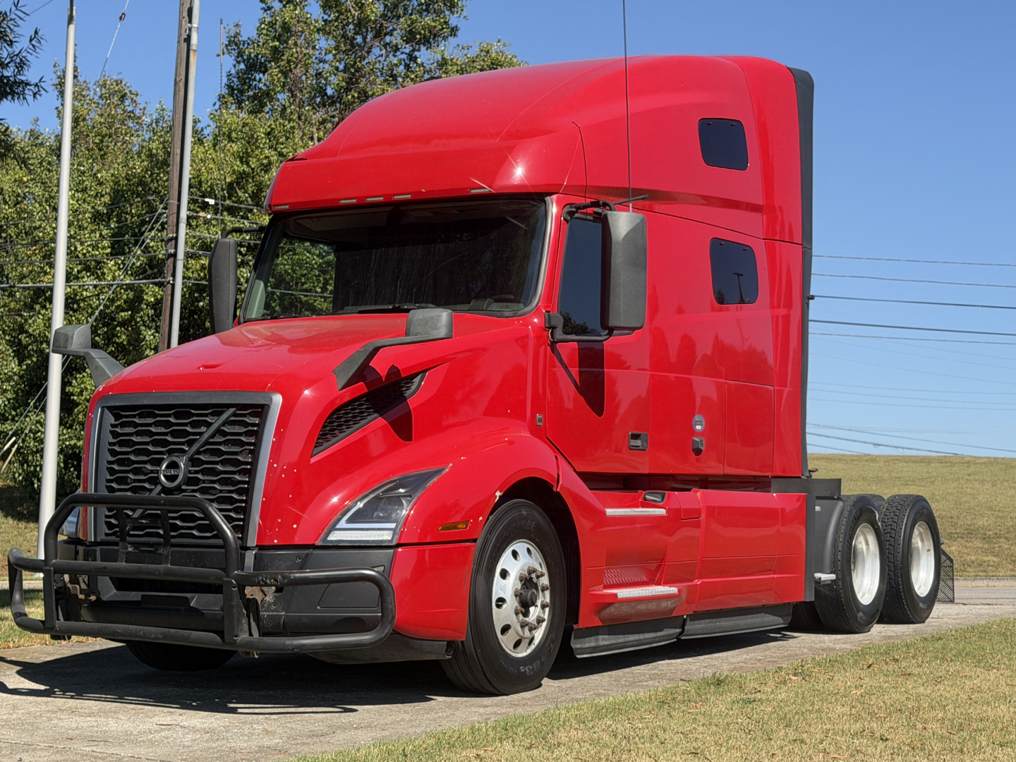 Volvo VNL64T760 2022 semi-truck tractor in red with sleeper cab, front grille, and dual rear axles; image shows left front view.