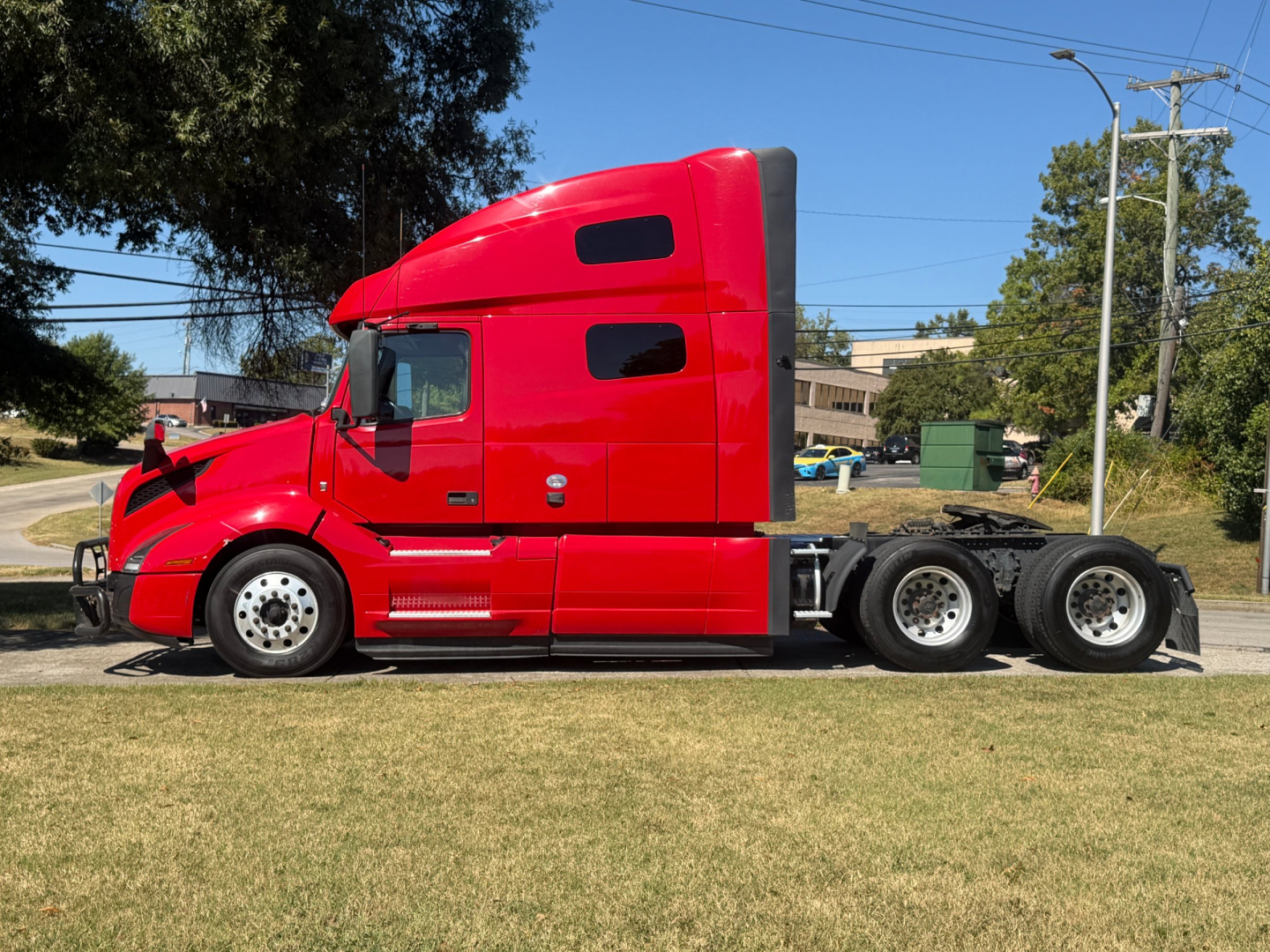 Volvo VNL64T760 truck side view showing red sleeper cab and dual rear axles.