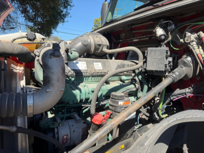 Volvo VNL64T760 engine bay showing diesel engine with green components, hoses, and wiring harnesses