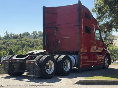 Volvo VNL64T760 sleeper tractor rear and side view showing triple rear axles and red cab.