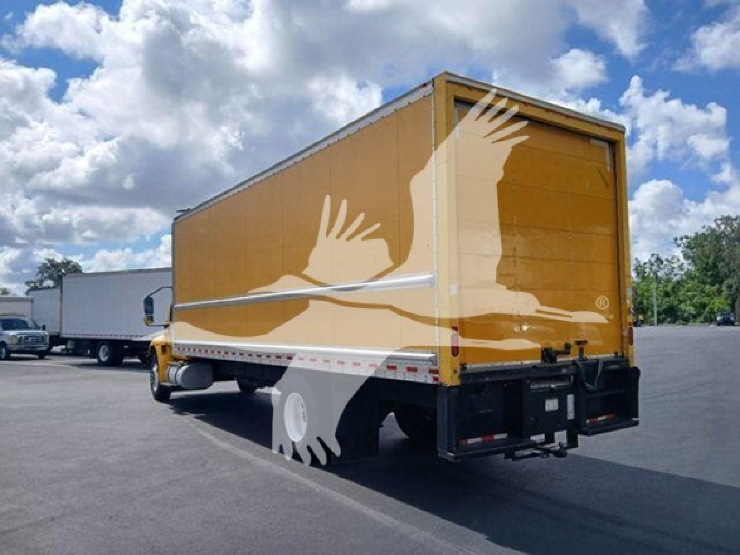 Truck body rear and side view of a yellow box truck on a paved lot, International MV model, with stock number T76455 and VIN visible in listing.