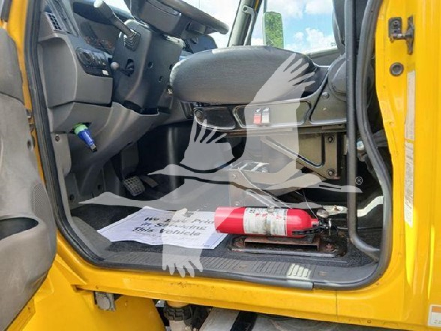 Cab interior of a 2020 International MV trucks showing front seat, open door, floor mat, and a red fire extinguisher mounted on the floor area.