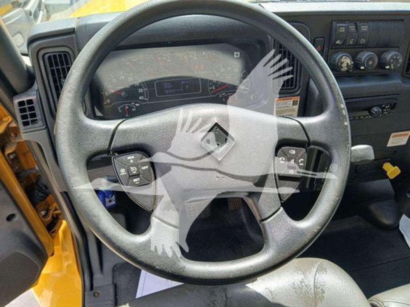 Truck interior: steering wheel with Renault logo, dashboard gauges, and control panels in view; vents and center console visible.