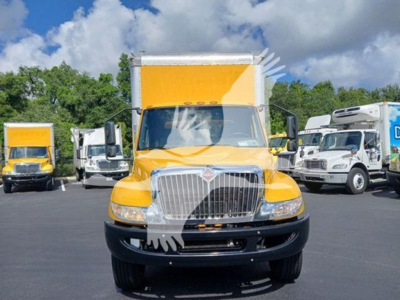 orange 2020 International MV box truck front view with chrome grille and headlights, in a dealership lot with other trucks in background.