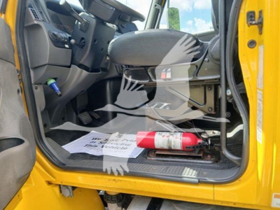 Cab interior of a 2020 International MV trucks showing front seat, open door, floor mat, and a red fire extinguisher mounted on the floor area.