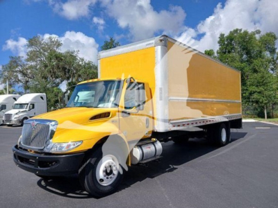 Box truck with yellow cab and box in service showing International MV logo and dual rear wheels.
