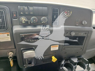 Dashboard of a 2020 International MV box truck showing instrument cluster, climate controls, ignition, and gear selector with warning labels.