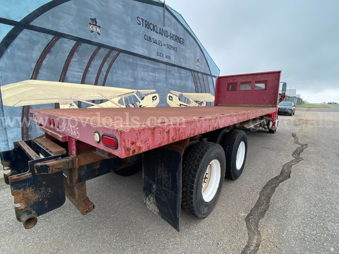 Flatbed trailer attached to Freightliner M2 106 chassis with dual rear wheels and red stake bed.
