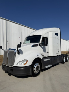 Kenworth T680 tractor trailer in white, front left view, with sleeper cab and large grille.