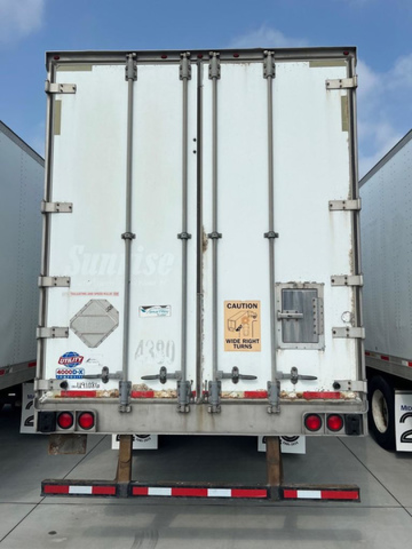 Rear view of a white cargo trailer with closed double doors and multiple latches.