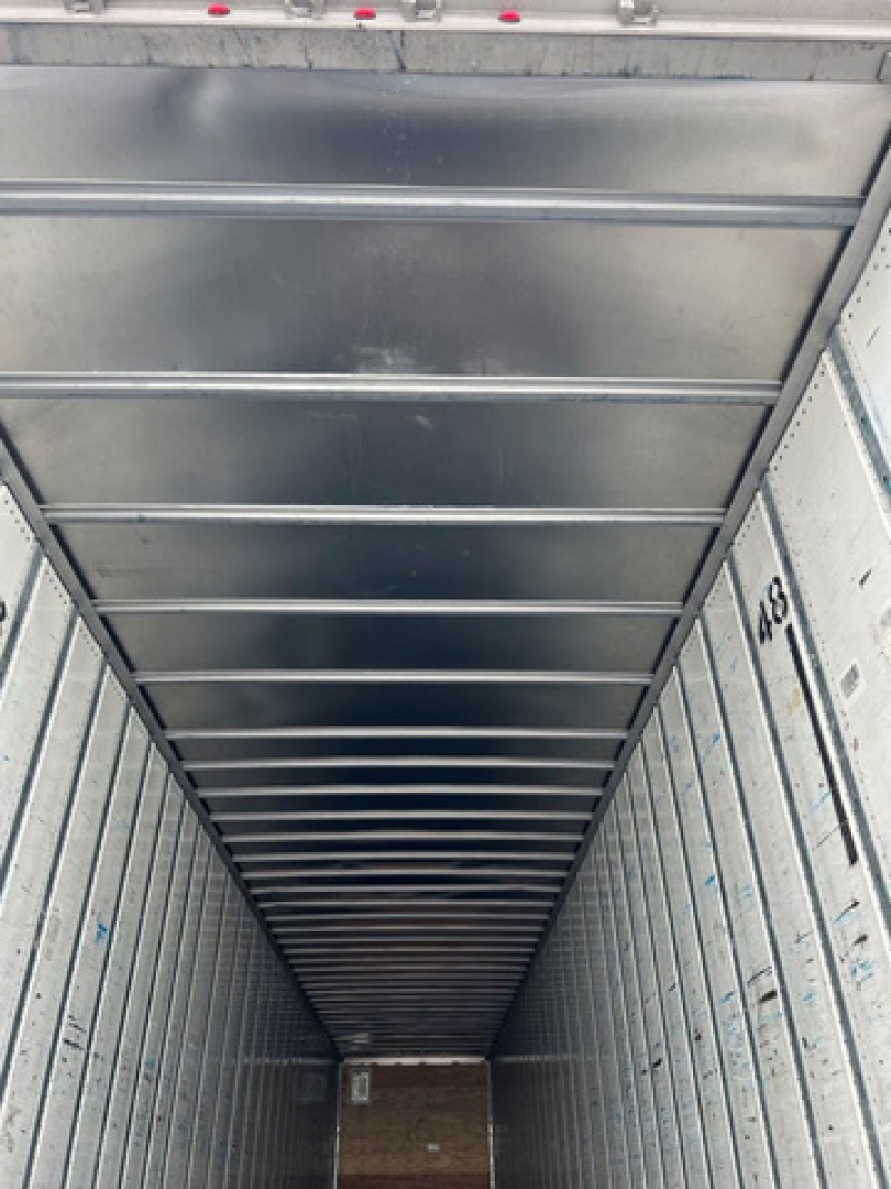 Van trailer interior with vertical ribbed walls and ceiling; no readable labels or fluid markings visible.