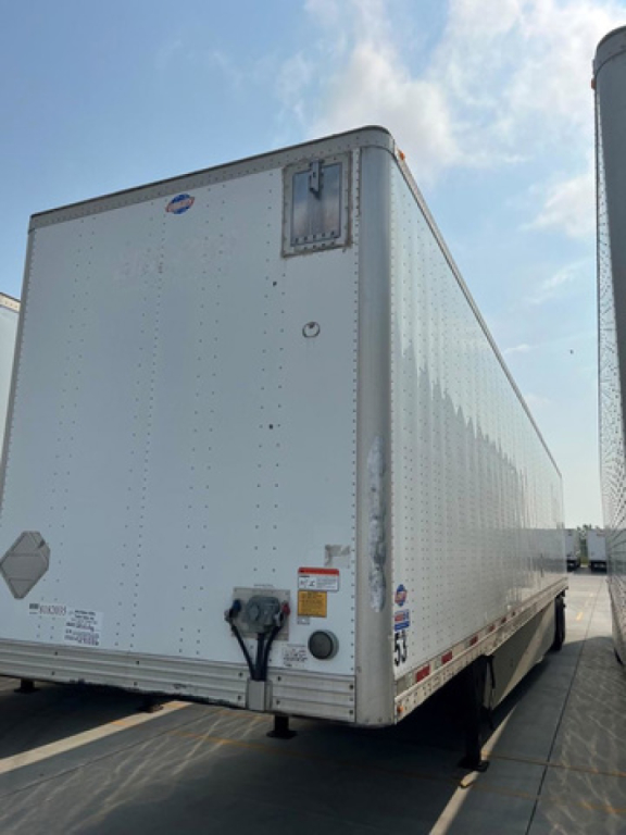 Utility van trailer showing rear and side panels with riveted aluminum exterior, DOT rear bumper, and dual landing gear.
