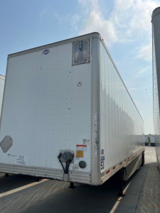 Utility van trailer showing rear and side panels with riveted aluminum exterior, DOT rear bumper, and dual landing gear.
