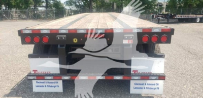 Flatbed trailer rear showing taillights and mud flaps with Kentucky-based dealer branding and reflective stripes.