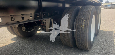 Trailer axle and tandem wheels of a new Dorsey Steel Air Sliding tandem flatbed trailer showing dual rear tires and white wheel rims.