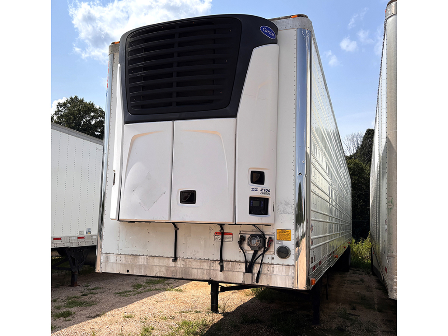 Front view of a white Utility 3000R refrigerated trailer with a black cooling unit on the front, electrical box and hoses resembling a reefer trailer.